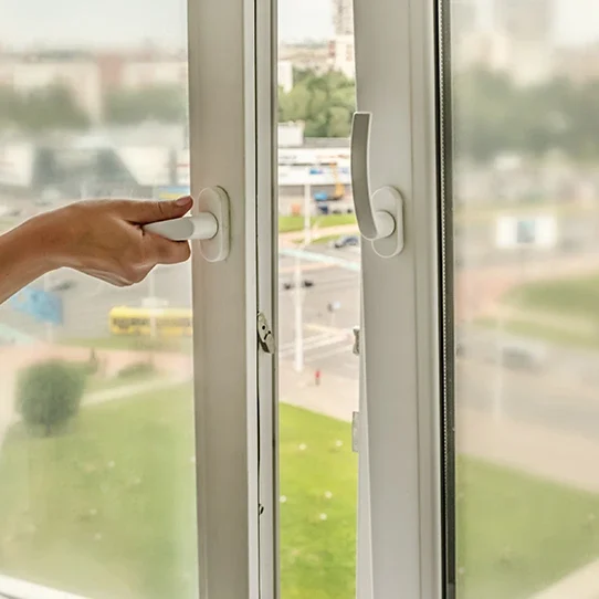 Femme réduisant les nuisances sonores en fermant une fenêtre