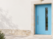 Porte d’entrée contemporaine bleu clair sur une façade française sobre, photographiée en lumière naturelle.