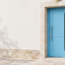 Porte d’entrée contemporaine bleu clair sur une façade française sobre, photographiée en lumière naturelle.